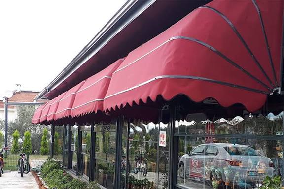 Kafe vitrini önünde açık körüklü tente; kumaş accordion gibi katlanır 6